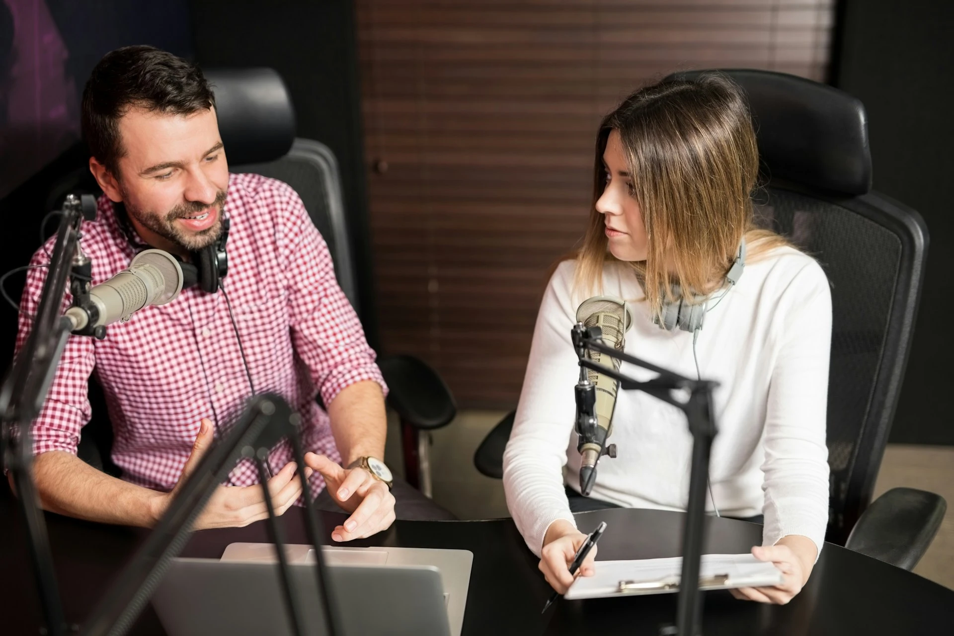 Dos locutores o podcasters conversando en un estudio de grabación frente a micrófonos.